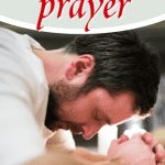 man with head bowed and hands folded on Bible
