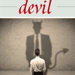 man facing a wall looking at a shadow of the devil