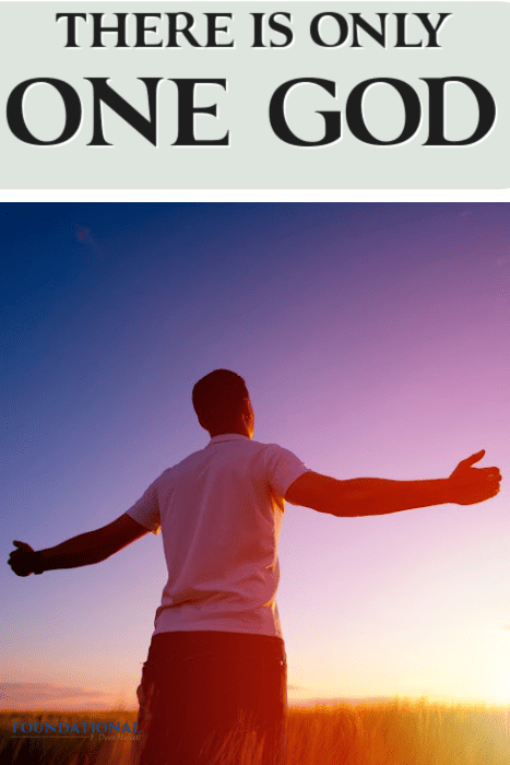 Man in white t-shirt standing against sunset with arms raised