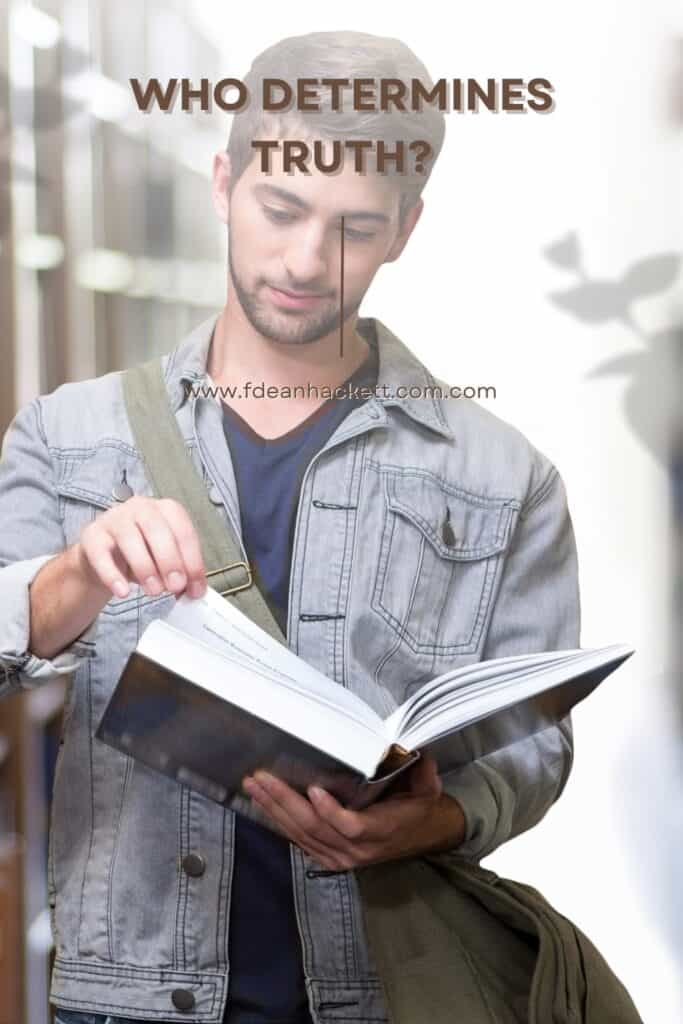 Man standing in library looking at a book