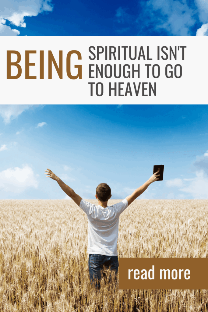 Man in a field with hands raised holding up a Bible