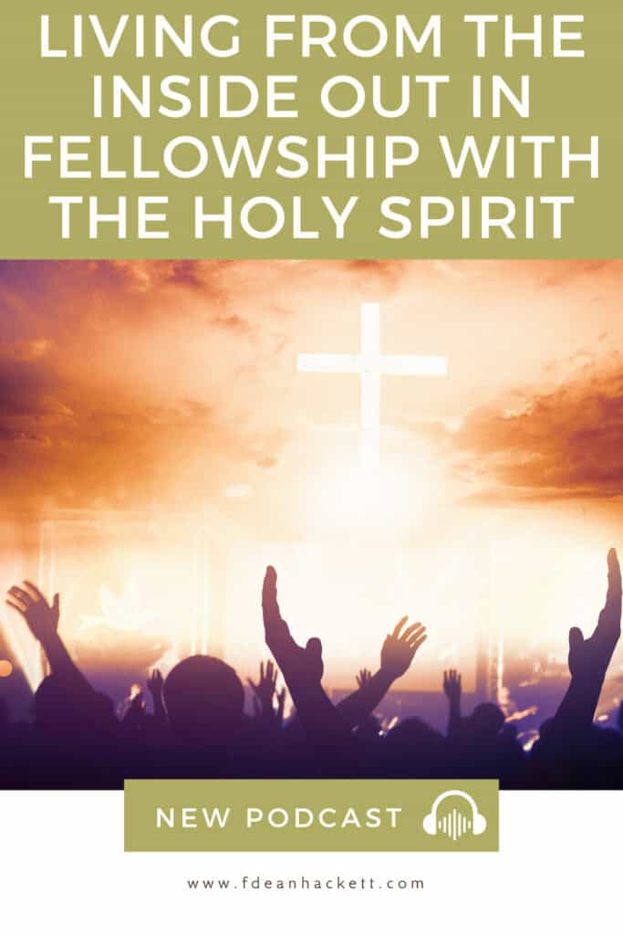 group of people raising their hands - a lit up cross in the background